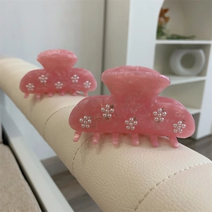 Détail de pinces à cheveux en acétate rose avec fleurs en perles et strass brillants