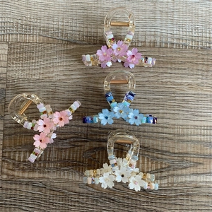 Floral hair claw clip with colorful rhinestones and pearls on wood background