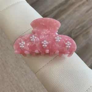 Détail de la pince à cheveux en acétate rose marbré avec fleurs de perles