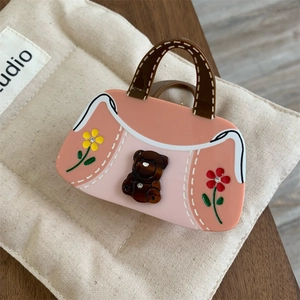 Détail de la pince à cheveux en forme de sac à main rose avec ours et fleurs