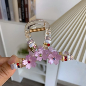 Detail of floral hair claw clip featuring purple cherry blossoms and colorful rhinestones