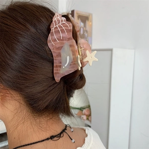 Detail of pink shell hair claw with starfish accent on hair in modern indoor setting