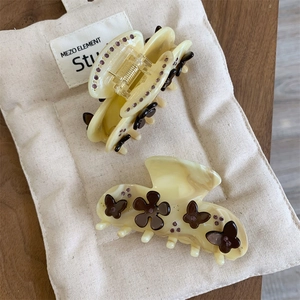 Close-up of acetate flower hair claw clips with marble texture on a canvas bag