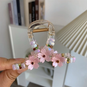 Close-up of translucent cherry blossom hair claw with pink petals and colorful rhinestones