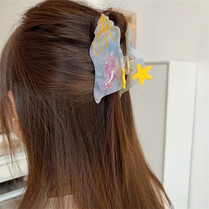 Detail view of marble blue conch hair claw clip with yellow starfish on hair