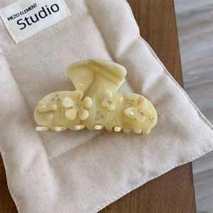 Detail of cream marble hair claw clip with 3D white flowers and golden accents