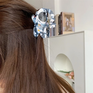 Pince à cheveux astronaute en acétate avec motif marbré bleu et blanc sur cheveux bruns