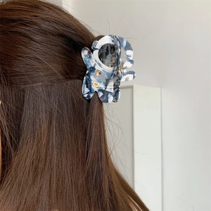 Détail d'une pince à cheveux astronaute avec motif marbre bleu sur cheveux bruns