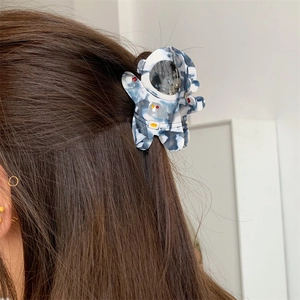 Détail d'une pince à cheveux astronaute en acétate marbré bleu sur les cheveux d'une femme