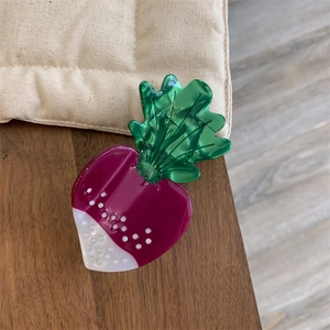Détail de la pince à cheveux en acétate en forme de betterave avec feuilles vertes et corps violet
