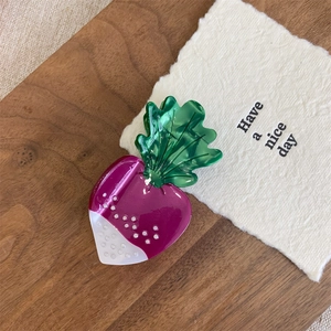 Vue détaillée d'une pince à cheveux en acétate en forme de betterave violette et verte