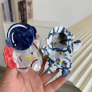 Détails de deux pinces à cheveux uniques en forme d'astronaute avec des textures en acétate