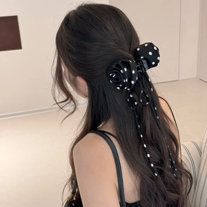Pince à cheveux élégante à pois noirs avec fleurs et longs rubans sur un modèle