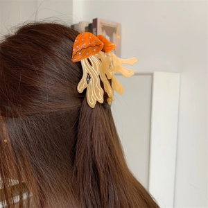 Close-up of bright orange jellyfish hair claw clip with rhinestones in dark hair