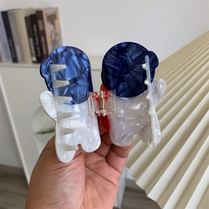 Détail de la pince à cheveux en acétate marbré bleu et blanc au design d'astronaute