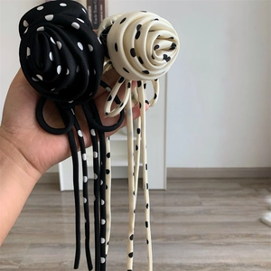 Gros plan sur d'élégantes pinces à cheveux rose à pois avec de longs rubans noir et blanc