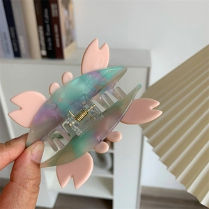 Detailed macro view of cherry blossom shaped acetate hair claw with iridescent finish