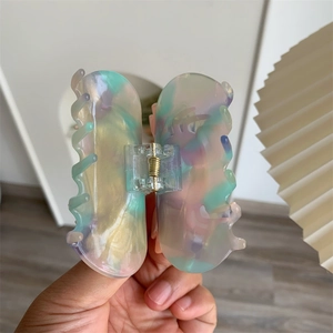 Detail of a translucent marble resin butterfly hair claw with a gold metal spring