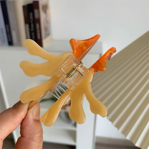 Detail view of a translucent orange jellyfish hair claw clip with a strong metal spring