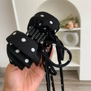 Détail d'une pince à cheveux à pois noirs et blancs avec de longs rubans élégants