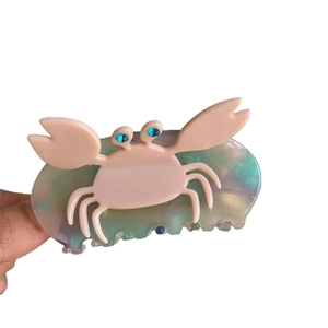 Cute pink crab claw hair clip with iridescent pearl finish and blue rhinestone eyes