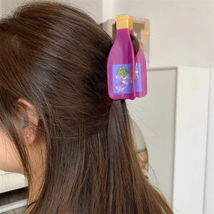 Detail view of a purple wine bottle shaped hair claw clip with grape pattern on brown hair