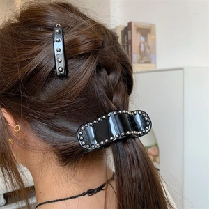 Détail de pinces à cheveux en acétate noir avec perles argentées et style punk poli