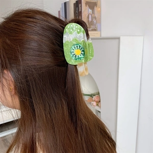 Close-up of kiwi ice cream shaped acetate hair claw clip worn on a model's hair