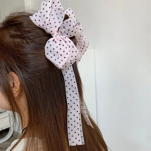 Close-up of a pink polka dot tulle bow hair claw clip with long streaming ribbons