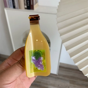 Detail of wine bottle acetate claw clip featuring purple grape patterns and amber finish