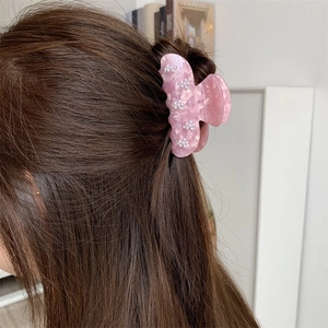 Nahaufnahme einer Haarklammer aus rosa Acetat mit Perlenblumen im Haar getragen
