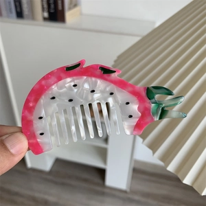 Dettaglio del pettine per capelli a forma di frutto del drago in acetato rosa e bianco
