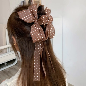 Brown polka dot bow hair claw clip with tassels shown on long hair from a back view