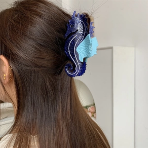 Pince à cheveux hippocampe bleue pailletée portée sur de longs cheveux bruns