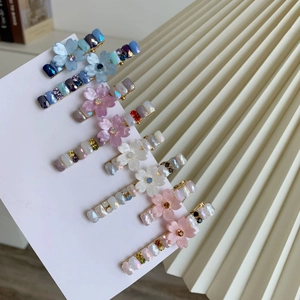 Vue détaillée de six barrettes à fleurs en strass avec pétales pastel et base dorée