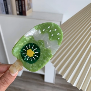Detail of kiwi popsicle hair claw made of green marbled acetate with fruit patterns