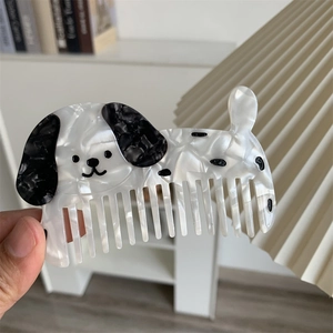 Dettaglio di un pettine creativo a forma di cucciolo in acetato con texture marmorizzata