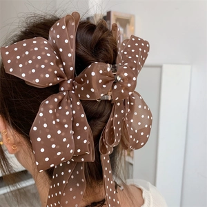 Close-up of a large brown polka dot bow hair claw clip styled on a woman's hair