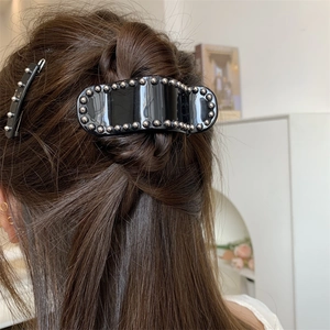Ensemble de pinces à cheveux noires avec clous argentés portées sur cheveux longs