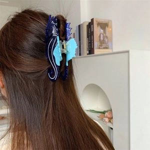 Détail d'une pince à cheveux hippocampe bleue pailletée sur de longs cheveux bruns