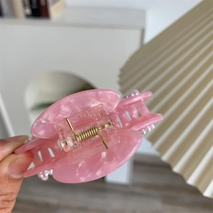 Detailansicht der Haarspange aus rosa Marmor-Acetat mit Perlen und goldener Metallfeder