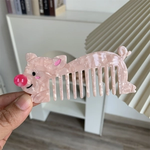 Dettaglio di un pettine per capelli a forma di maiale in acetato rosa marmorizzato