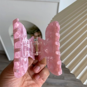 Nahaufnahme der Haarspange aus rosa Acetat mit Marmormuster und goldener Metallfeder