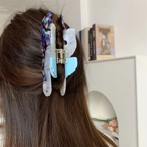 Détail d'une pince à cheveux hippocampe en acétate marbré bleu sur les cheveux d'un mannequin