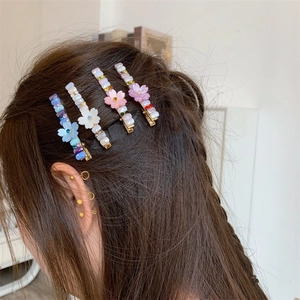 Détail de quatre pinces à cheveux florales avec fleurs mates et perles sur le côté