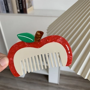 Dettaglio di un pettine creativo a forma di mela in acetato marmorizzato rosso e denti