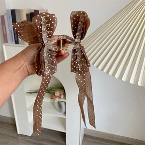 Detail of large transparent claw clip with brown polka dot bow and long ribbons