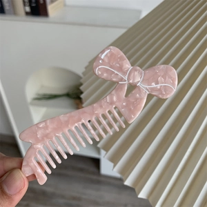 Dettaglio di un pettine per capelli in acetato rosa marmorizzato dal design a fiocco