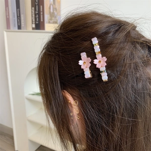 Set de barrettes à fleurs de cerisier roses et cristaux sur cheveux blonds ondulés