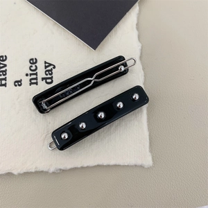 Détail de barrettes à cheveux en acétate noir brillant ornées de perles métalliques